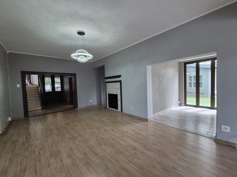 Spacious living area featuring laminate flooring, a central fireplace with decorative tiling, and direct access to an outdoor patio through glass doors.