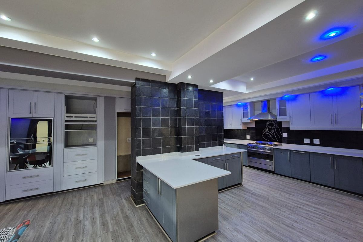 Modern kitchen featuring a central island, stone countertops, built-in oven, gas stove with extractor, and contemporary cabinetry with integrated lighting.