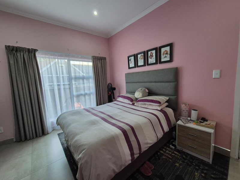 A bedroom featuring tiled flooring, recessed ceiling lights, and a sliding glass door with curtains, providing access to the exterior.