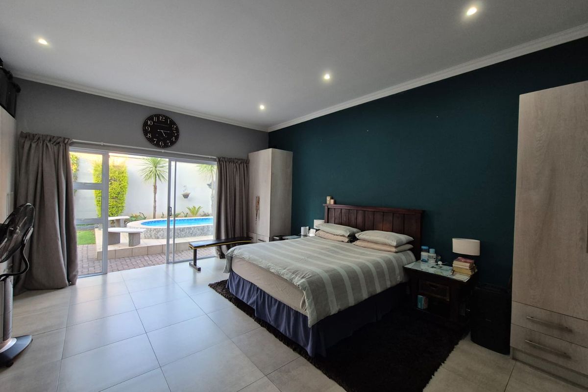 Spacious bedroom featuring tiled flooring, recessed lighting, and large sliding glass doors providing direct access to the outdoor pool area.