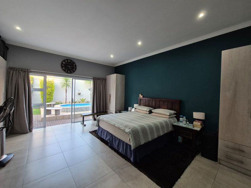 Spacious bedroom featuring tiled flooring, recessed lighting, and large sliding glass doors providing direct access to the outdoor pool area.