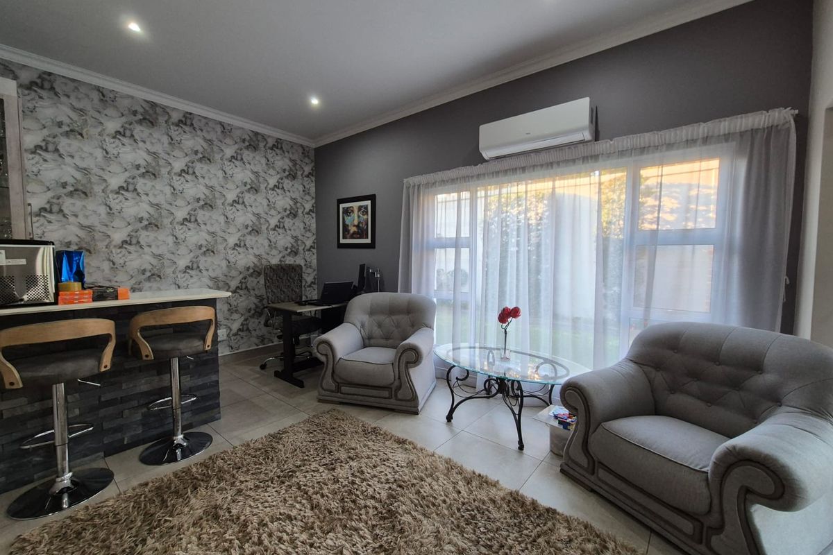 A comfortable living area featuring tiled floors, recessed lighting, a split-system air conditioner, and a breakfast bar with a decorative feature wall.