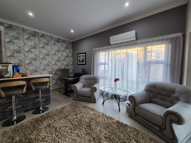 A comfortable living area featuring tiled floors, recessed lighting, a split-system air conditioner, and a breakfast bar with a decorative feature wall.