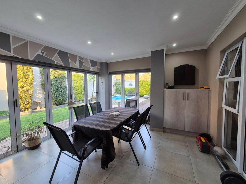 Bright open-plan dining area featuring large aluminium stacker doors that provide seamless access to the garden and pool area.