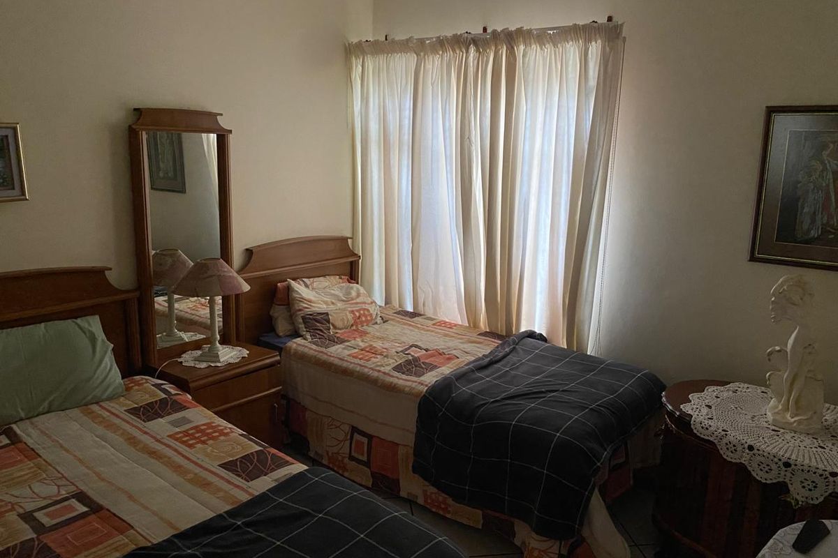 A bedroom featuring tiled flooring and a window with curtains, providing a functional space for rest.