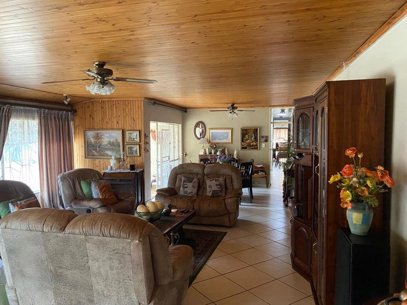 Open plan living area featuring timber paneled ceilings and walls, tiled flooring, and ceiling fans, creating a traditional and cozy atmosphere.
