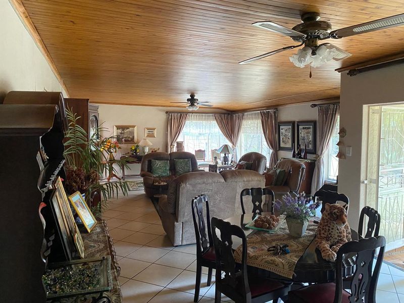 Spacious open-plan living and dining area featuring a warm timber-clad ceiling, ceramic tiled flooring, and direct access to the outdoor space via sliding doors.