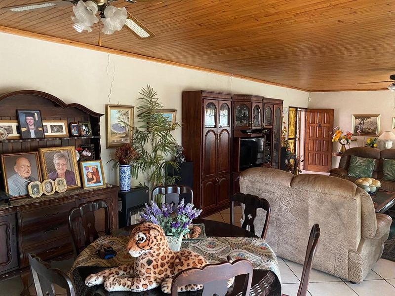 Open plan living and dining area featuring a timber ceiling, ceiling fan, and tiled flooring, with a visible wall crack requiring attention.