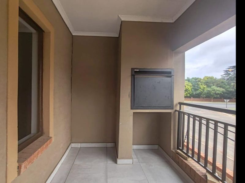 A covered balcony featuring tiled flooring, a built-in braai, and a metal balustrade overlooking the street.