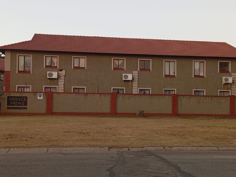 Front exterior view of Morris Mews apartment complex featuring a tiled roof, perimeter wall, and multiple wall-mounted air conditioning units.
