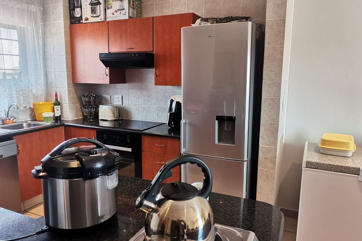 A functional kitchen featuring granite countertops, dark wood cabinetry, a built-in oven, and a tiled backsplash, offering a practical layout for daily cooking.
