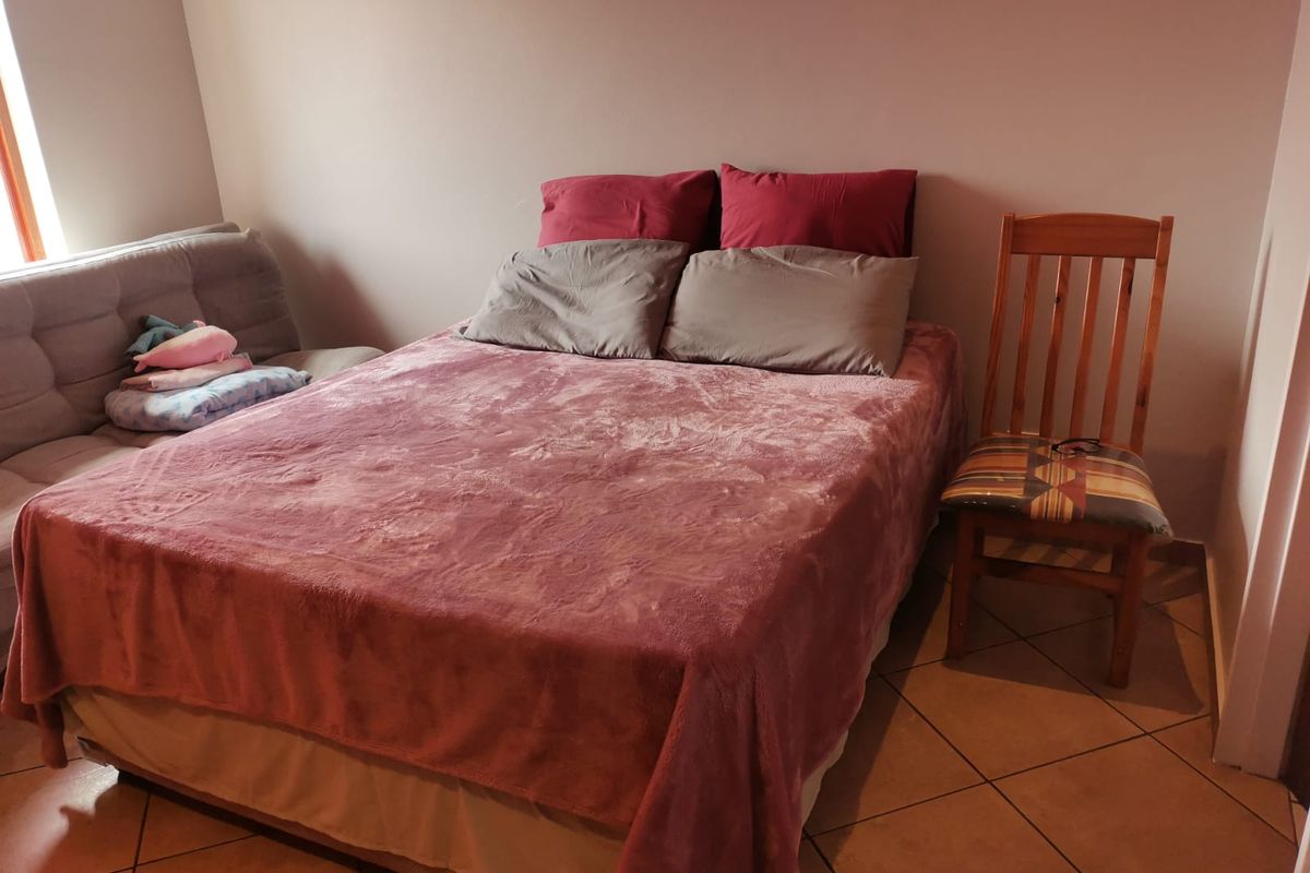 A bedroom featuring tiled flooring and neutral wall finishes, providing a functional space for rest.