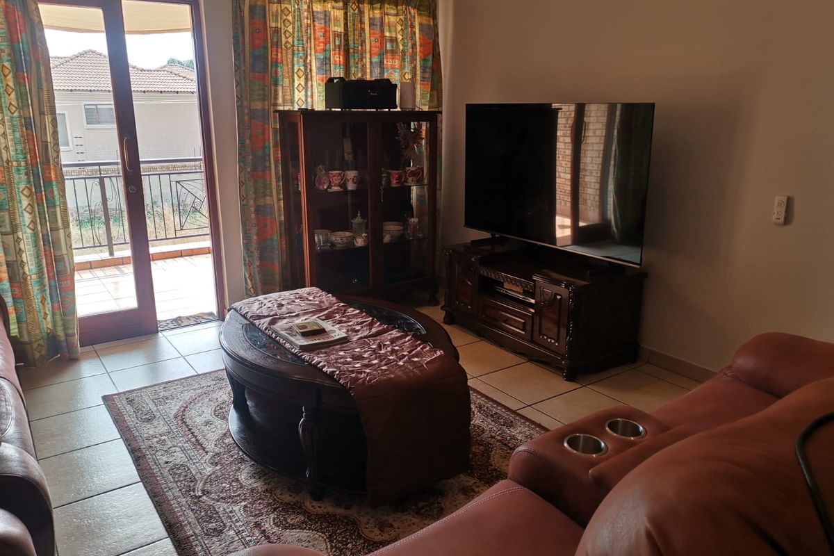 A comfortable living room featuring tiled flooring and a sliding glass door providing direct access to an outdoor balcony area.