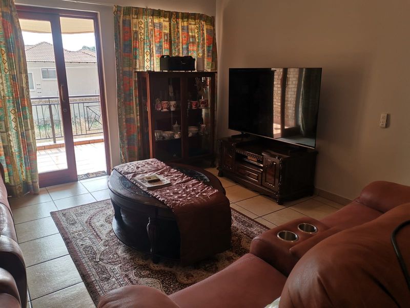 A comfortable living room featuring tiled flooring and a sliding glass door providing direct access to an outdoor balcony area.