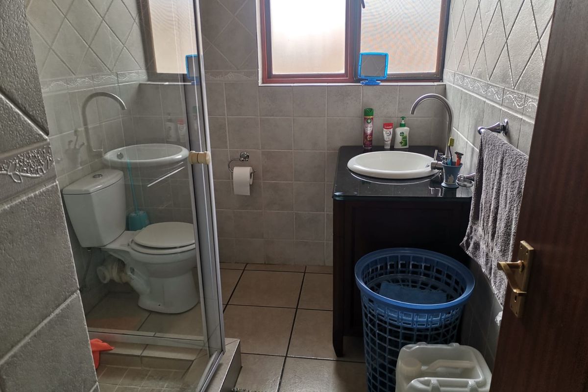 A compact bathroom featuring a shower enclosure, a vanity with a basin, and tiled finishes throughout.