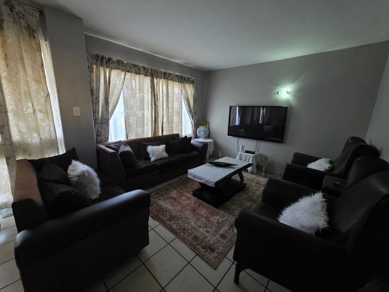 A comfortable living room featuring tiled flooring and a wall-mounted television setup, offering a functional space for relaxation.