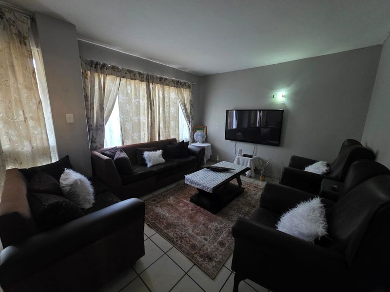 A comfortable living room featuring tiled flooring and a wall-mounted television, offering a functional space for relaxation.