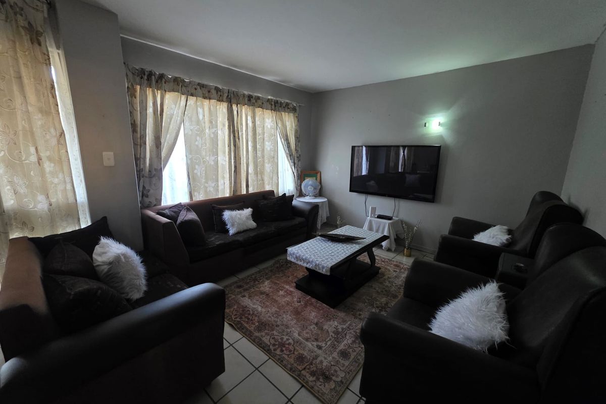 A comfortable living room featuring tiled flooring and a wall-mounted television, offering a functional space for relaxation.