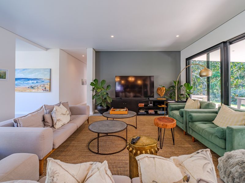 A bright and modern living room featuring a dark grey accent wall, recessed lighting, and large sliding glass doors opening to the garden.