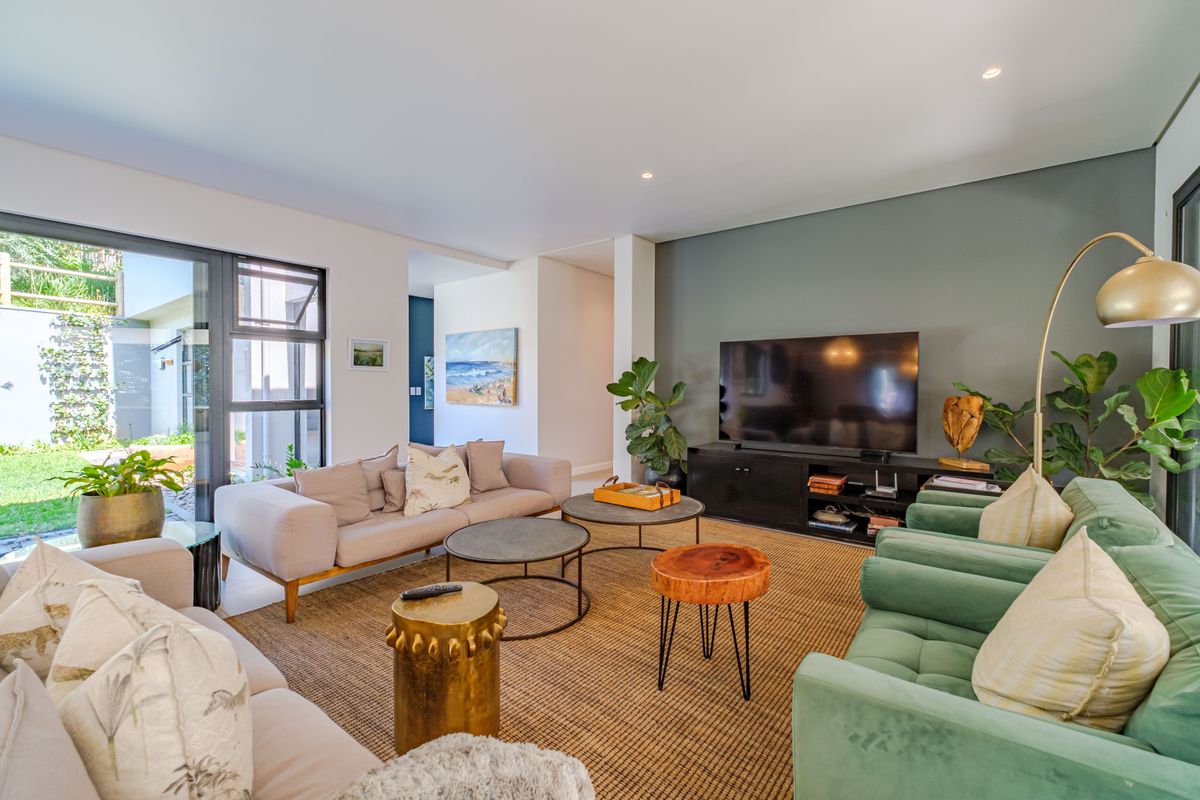 A bright and modern living room featuring an accent wall, recessed lighting, and large sliding glass doors providing access to the garden.
