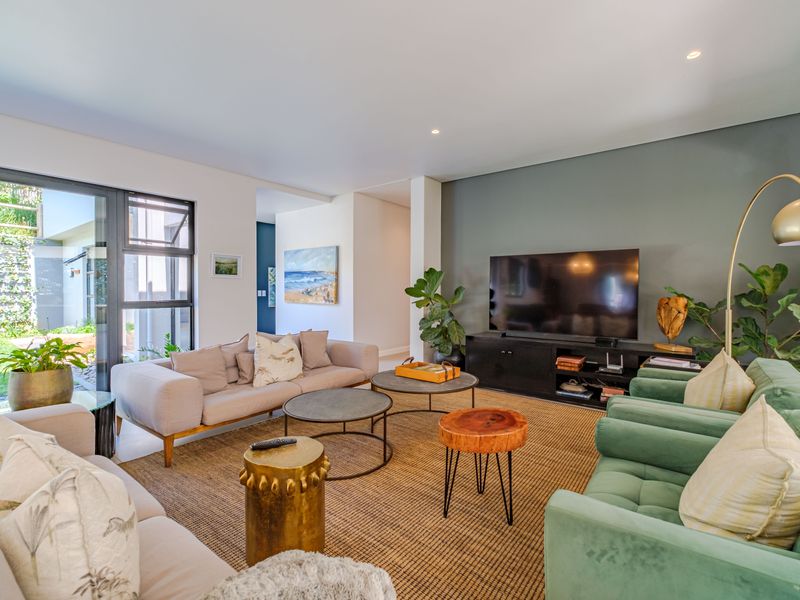 A bright and modern living room featuring an accent wall, recessed lighting, and large sliding glass doors providing access to the garden.