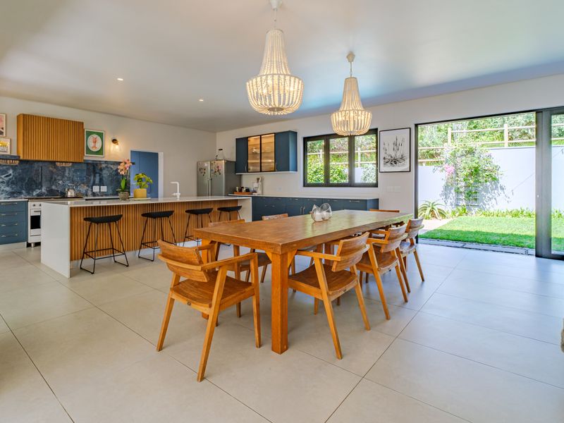 Spacious open-plan kitchen and dining area featuring modern cabinetry, stone countertops, a large island, and seamless access to the rear garden through sliding doors.