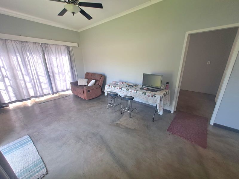 Spacious living area featuring concrete flooring, a ceiling fan, and large sliding glass doors providing natural light.