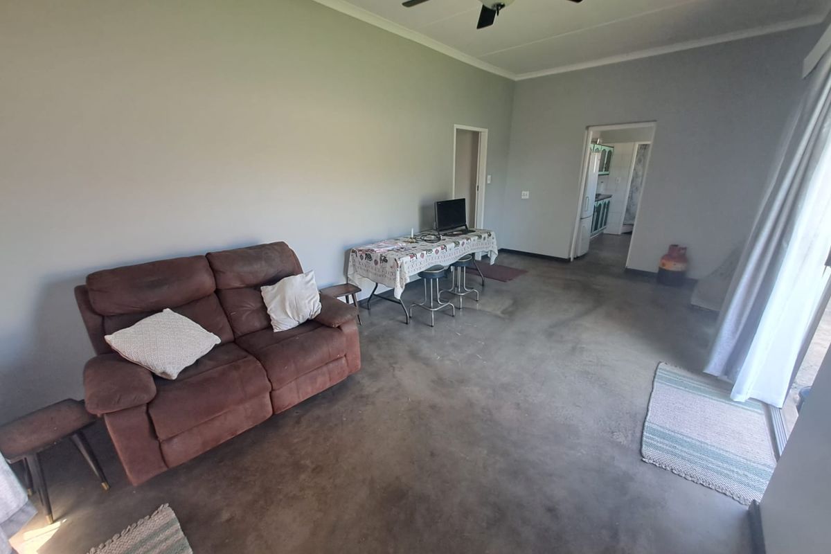 Open-plan living area featuring a ceiling fan and sliding glass door access, with unfinished concrete flooring throughout.