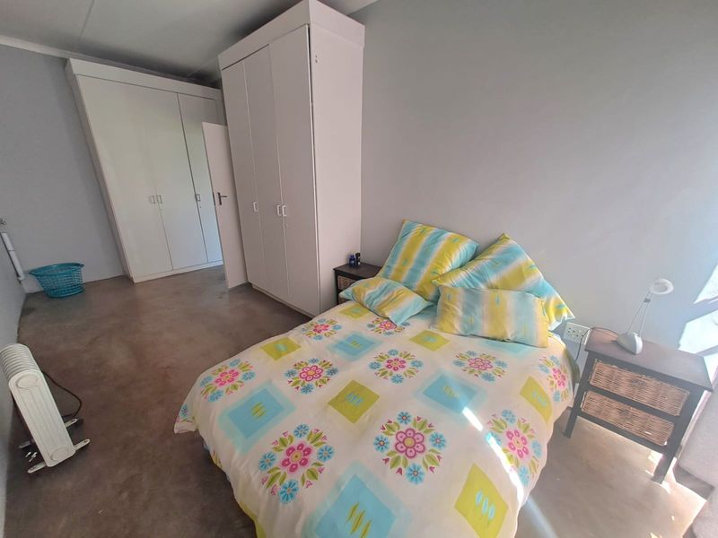 A bedroom featuring built-in cupboards and polished concrete flooring, offering a neutral base for interior design updates.