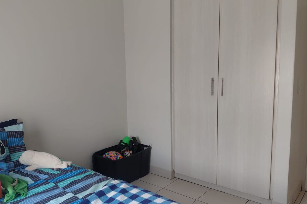 A bedroom featuring neutral walls, tiled flooring, and a built-in wardrobe with white doors.