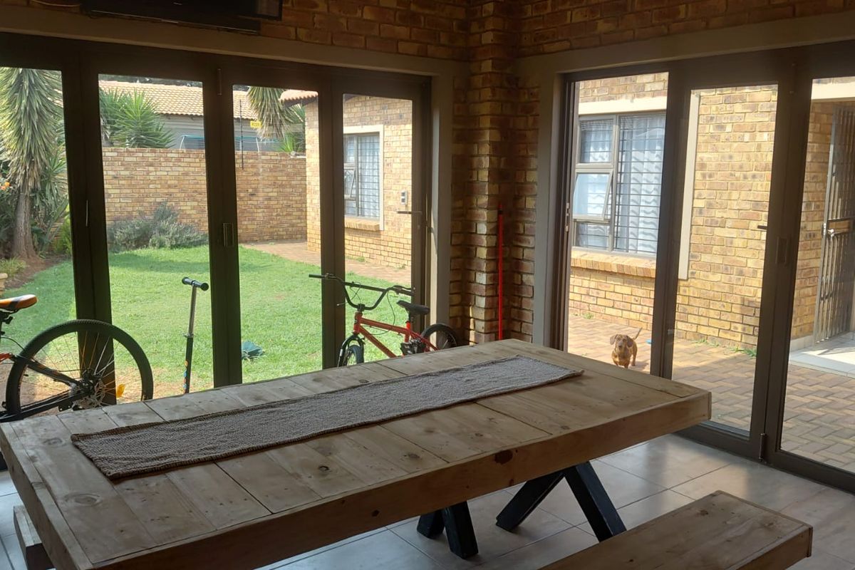 Living area featuring exposed brick walls and large aluminium stacker doors providing seamless access to the rear garden.