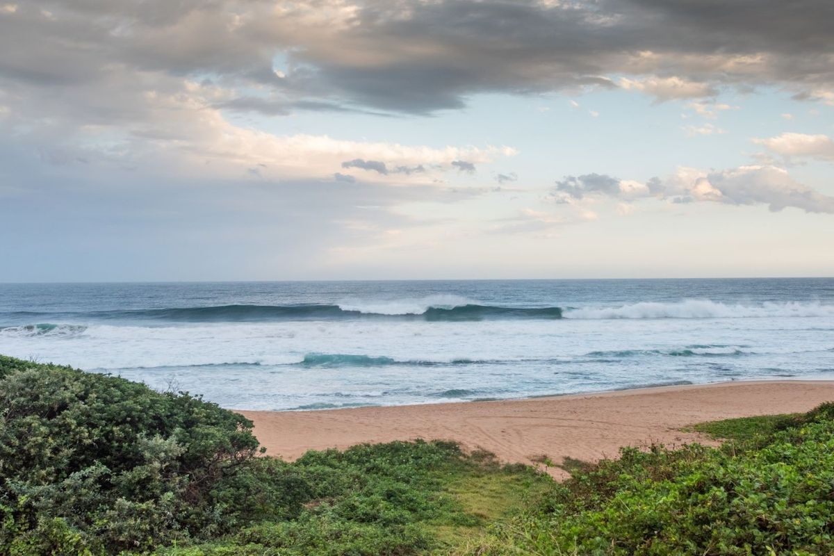 A scenic view of the ocean and sandy beach, showcasing the natural coastal landscape of the property.
