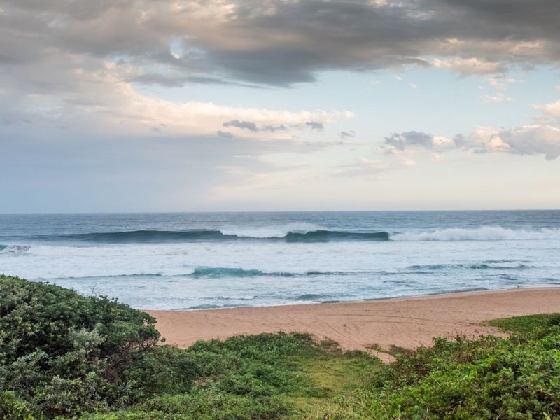 A scenic view of the ocean and sandy beach, showcasing the natural coastal landscape of the property.