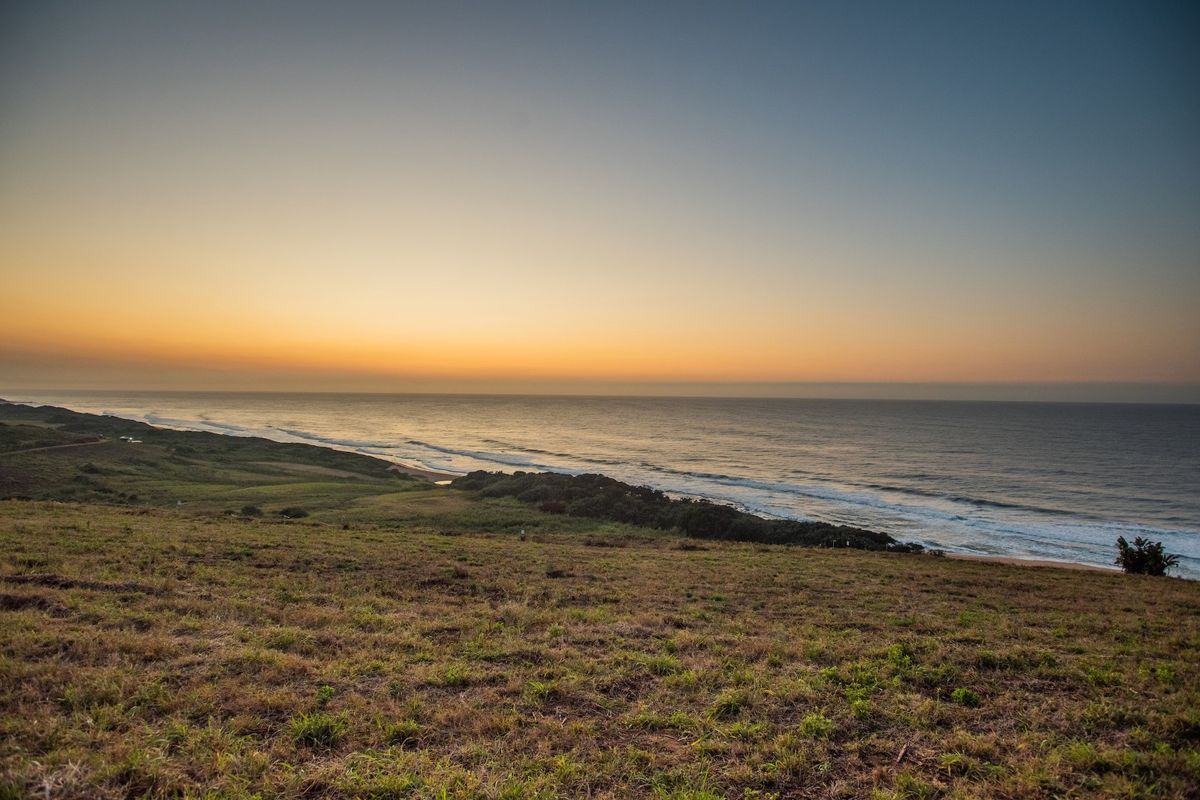 A scenic elevated view of the coastline and ocean at sunset, showcasing the natural landscape of the vacant residential property.