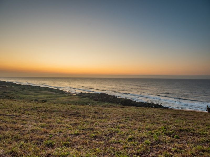 A scenic elevated view of the coastline and ocean at sunset, showcasing the natural landscape of the vacant residential property.