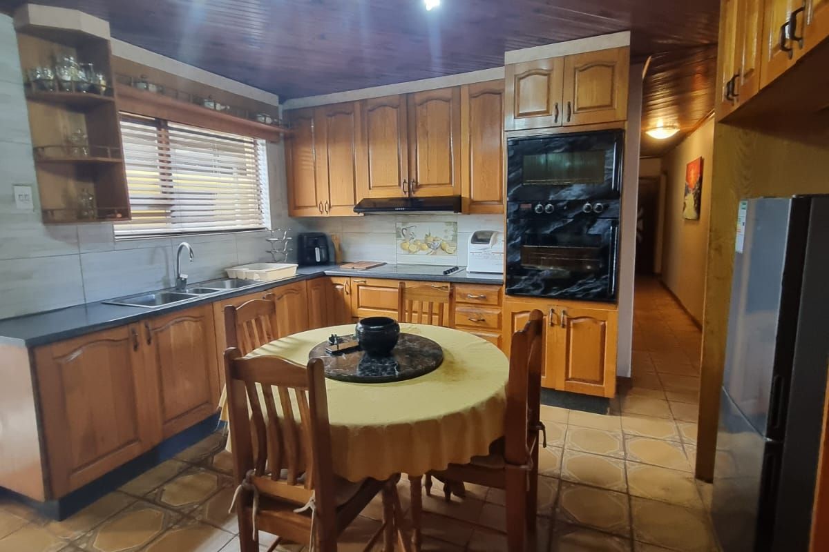 A traditional kitchen featuring wooden cabinetry, a double wall oven, tiled flooring, and a distinctive wooden tongue and groove ceiling.