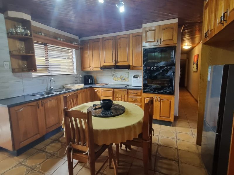 A traditional kitchen featuring wooden cabinetry, a double wall oven, tiled flooring, and a distinctive wooden tongue and groove ceiling.
