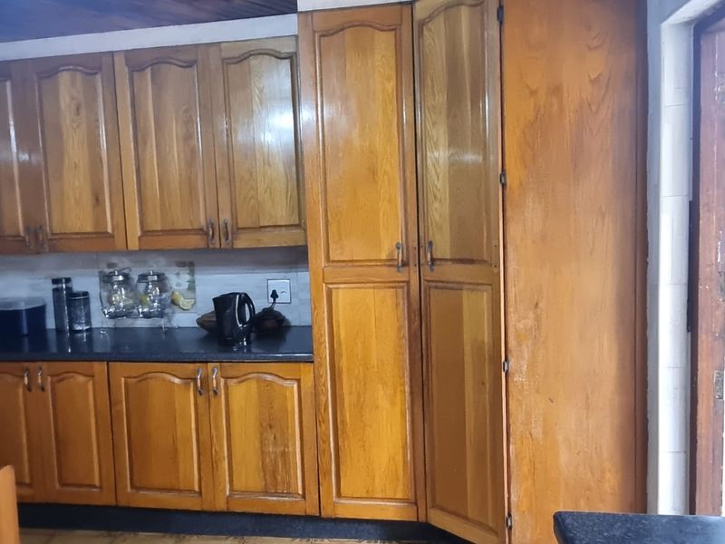 A functional kitchen featuring traditional timber cabinetry, dark laminate countertops, and a distinctive timber tongue and groove ceiling.