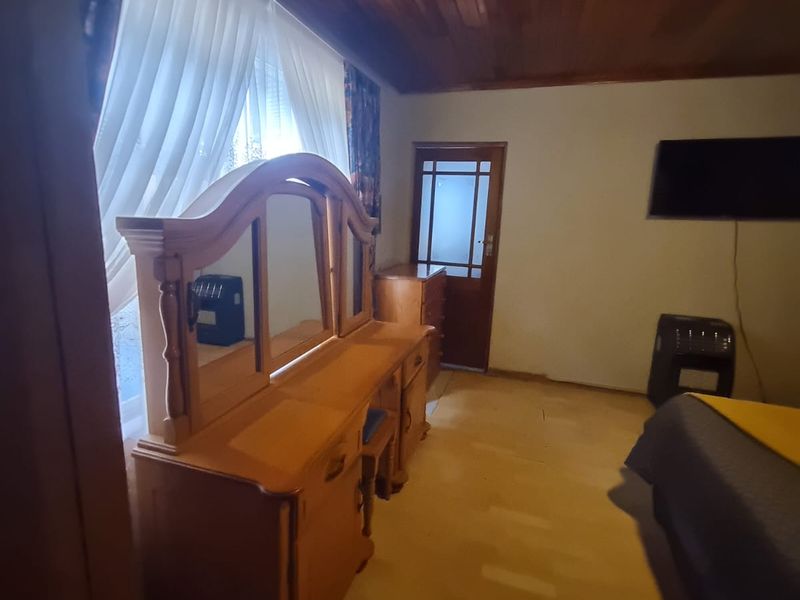 A bedroom featuring a distinctive timber-clad ceiling and a timber-framed glass door, offering a traditional aesthetic.