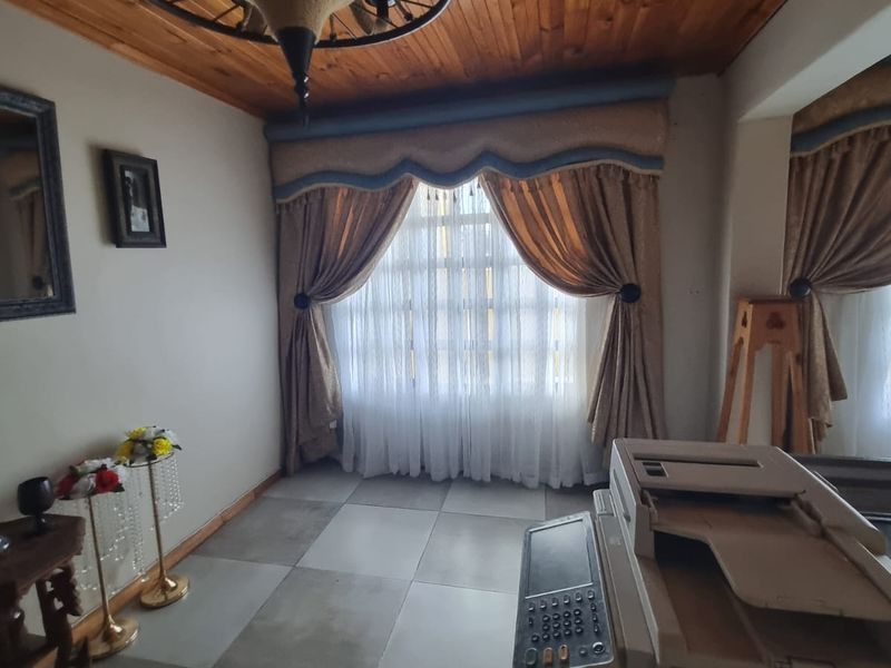 A living area featuring a timber-clad ceiling, tiled flooring, and a decorative chandelier, offering a warm and traditional aesthetic.
