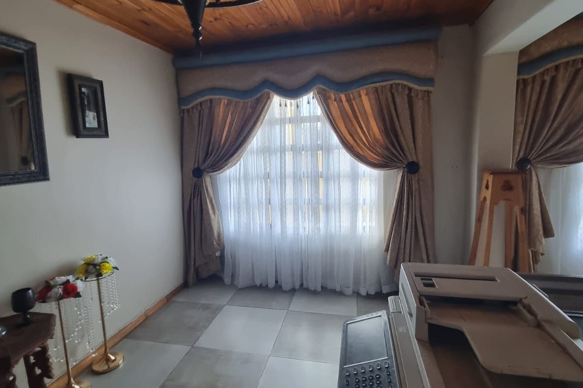 A living area featuring a timber-clad ceiling, tiled flooring, and a decorative chandelier, offering a warm and traditional aesthetic.