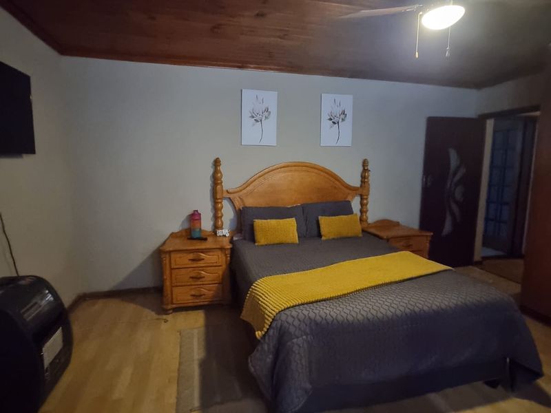 A bedroom featuring a timber-clad ceiling, ceiling fan, and laminate flooring.