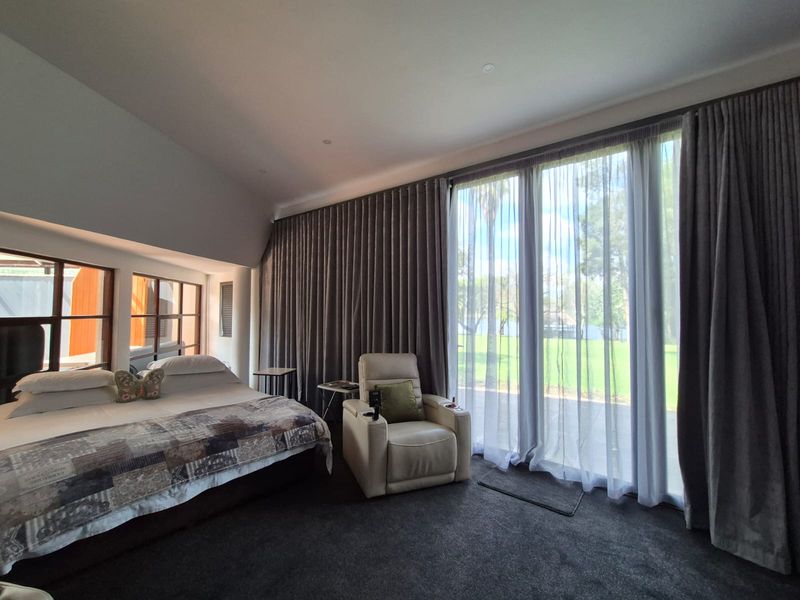 Spacious bedroom featuring floor-to-ceiling windows with full-length curtains, providing ample natural light and direct access to the outdoor area.