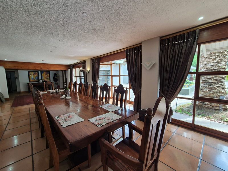 Spacious dining room featuring terracotta floor tiles, large timber-framed windows, and an exposed timber beam, offering a traditional aesthetic with garden views.