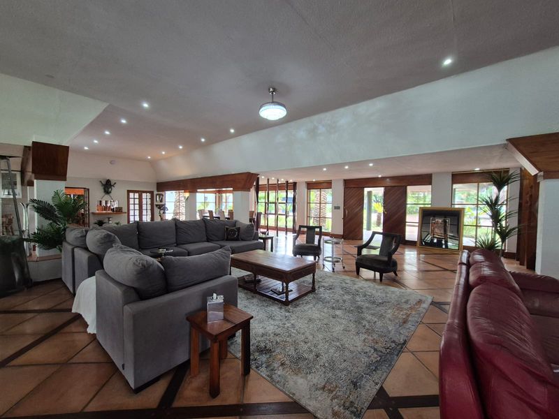 Spacious open-plan living area featuring terracotta tile flooring, vaulted ceilings, and extensive timber-framed glazing providing natural light and garden access.