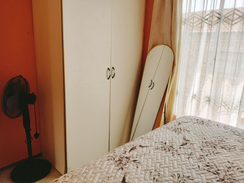 A bedroom featuring a built-in wardrobe and natural light from a window with curtains.