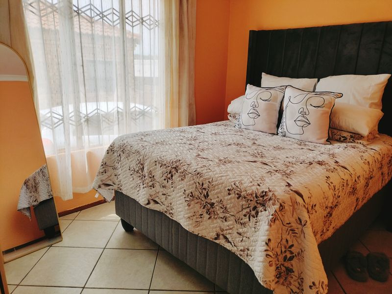 A cozy bedroom featuring tiled flooring and large windows that allow for natural light.