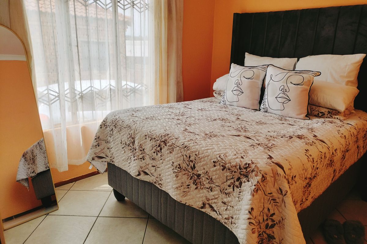 A cozy bedroom featuring tiled flooring and large windows that allow for natural light.