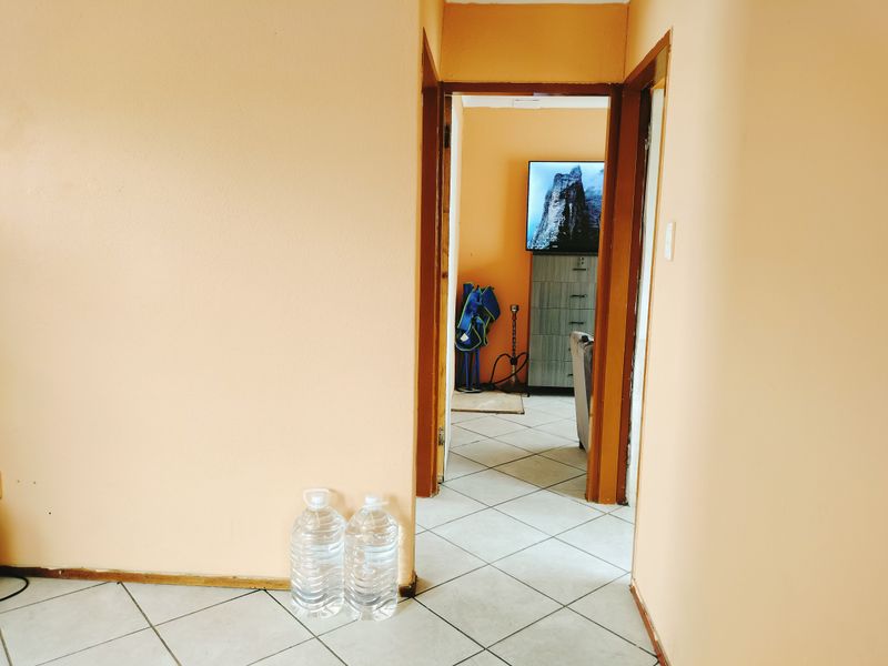 A view through a doorway into an adjacent room, featuring tiled flooring and plain wall finishes in a residential hallway setting.