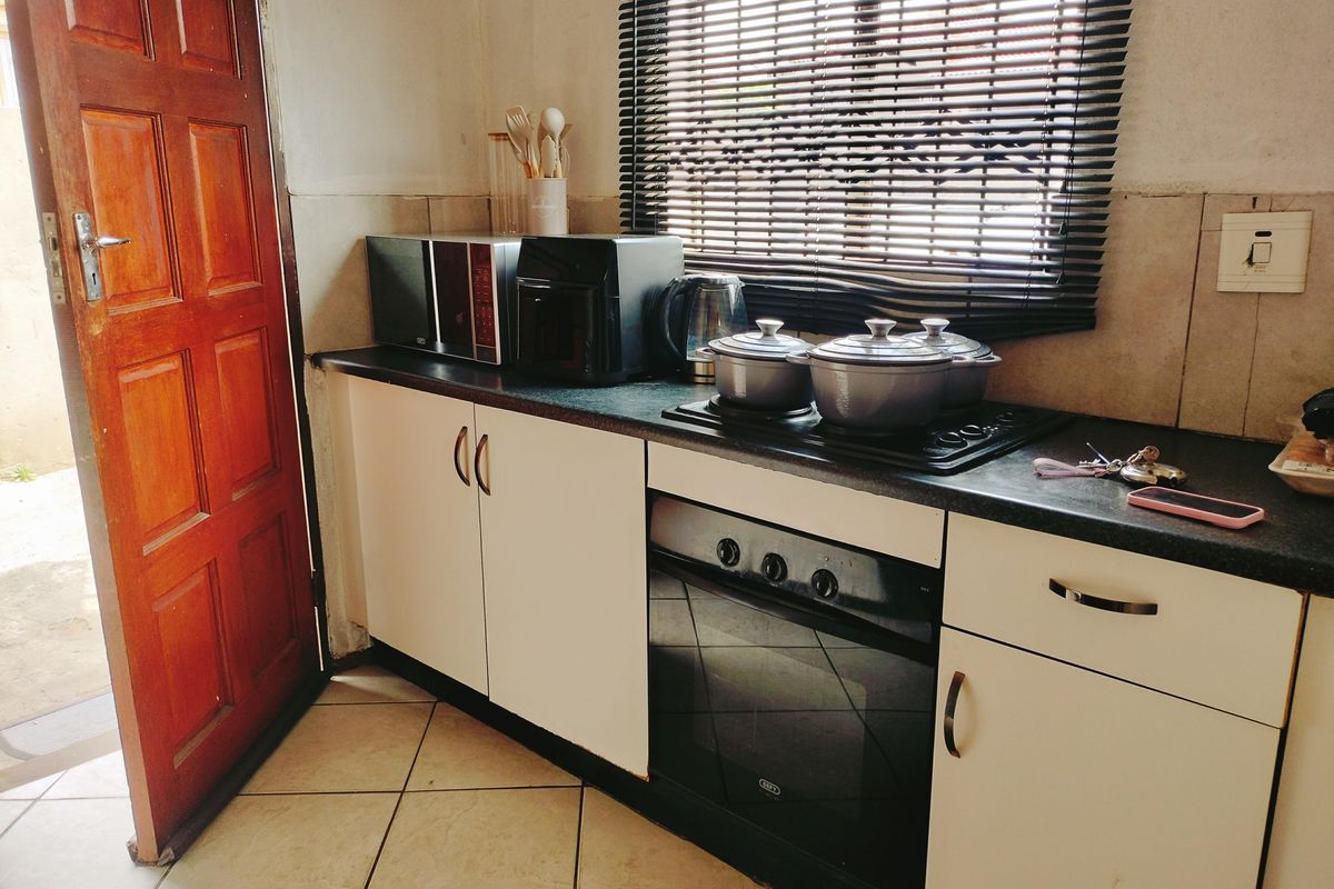 A functional kitchen area featuring built-in oven and hob, tiled flooring, and cabinetry with a tiled backsplash.